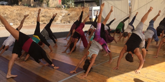 clase de yogahome en festival de yoga en canarias al aire libre en un suelo de madera con techo sin paredes laterales 