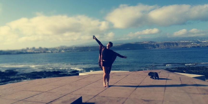 Sara Quintana con los brazos abirtos frente al mar y la montaña en Las Palmas de Gran canaria