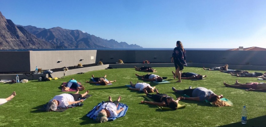 Sara Quintana (yogahome las palmas) guiando una sesión de yoga en rooftop con vistas al mar y la montaña